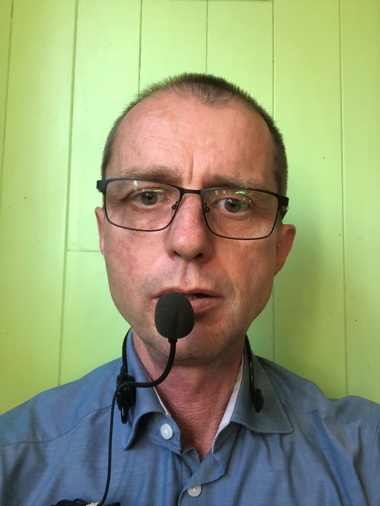 Stephen wearing a voice amplifier mic in front of lips, supported by a flexible stand worn around the neck